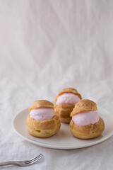 Homemade choux cream or cream puffs with strawberry cream on white background