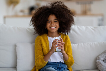 Healthy and cheerful little black girl drinking water
