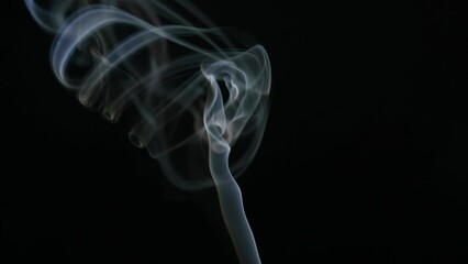 White smoke from incense stick flowing on black background