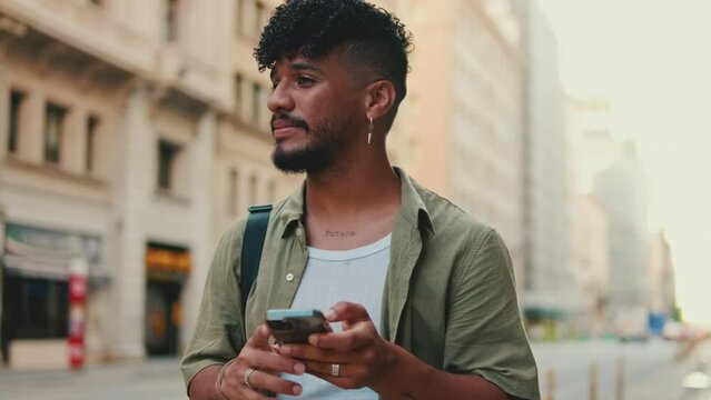 Young smiling man with beard dressed in an olive color shirt uses phone map app on the old city background