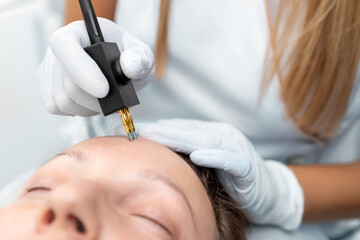 Close-up beautician doctor hand making anti-age face remodel procedure treatment with hardware...