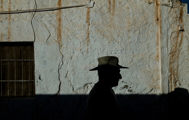 Portrait of adult man in cowboy hat against wall with sunlight and shadow