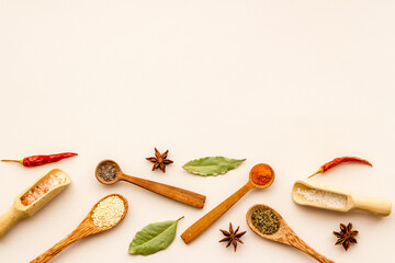Variety of colorful spices and herbs in wooden spoons on kitchen table, top view