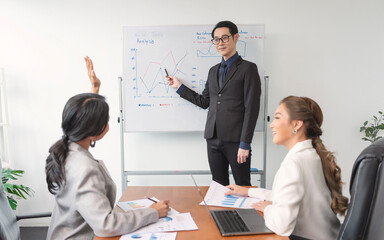 Asian businesspeople sit at desk in boardroom discuss financial paperwork at briefing, focused diverse colleagues brainstorm analyze ideas at team meeting in office, teamwork concept.