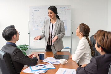 Asian businesspeople sit at desk in boardroom discuss financial paperwork at briefing, focused diverse colleagues brainstorm analyze ideas at team meeting in office, teamwork concept.