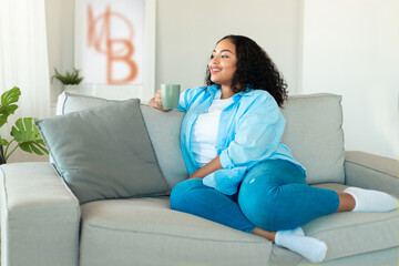 African American Woman Drinking Coffee Sitting On Couch At Home