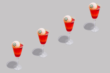 Halloween spooky red cocktails with bloody eyes on grey background. Festive drink. Halloween party composition in a minimalist style.