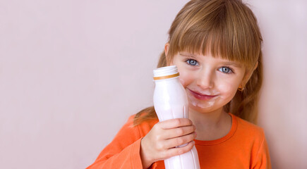 Portrait of a little beautiful girl with emotions on her face, her mouth stained with milk, holding a plastic bottle with a milk drink, yogurt or kefir, selective focus	