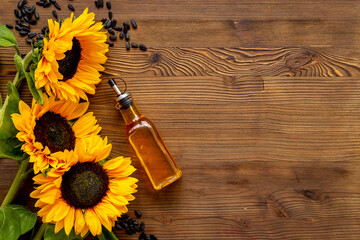 Top view of cooking oil with yellow sunflowers and black seeds
