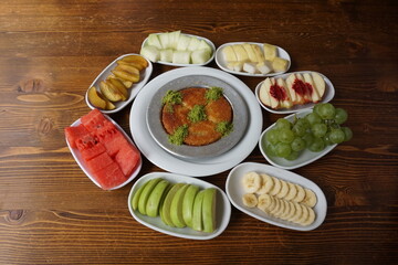 knafeh in the middle, fruit plates around it, traditional dessert