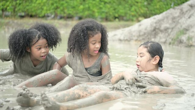 Children have fun playing in the mud in the community fields. with parents watching from a distance