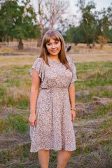 Fototapeta premium A young woman walks in a clearing. A walk in the park or forest. Outdoor recreation. The atmosphere of freedom and nature.