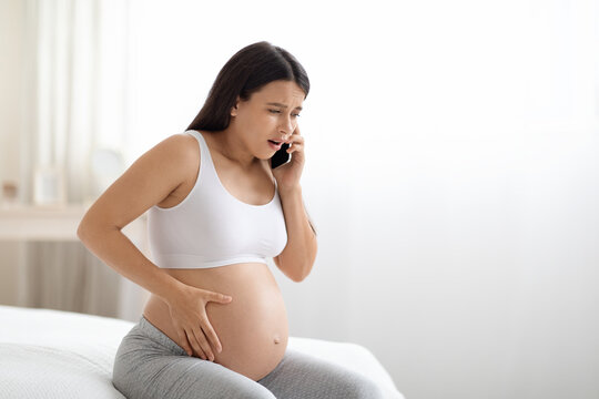 Young Pregnant Woman Feeling Some Pain And Discomfort, Calling Doctor