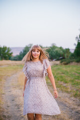 A young woman walks in a clearing. A walk in the park or forest. Outdoor recreation. The atmosphere of freedom and nature.