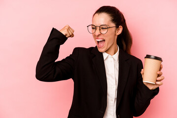 Young business caucasian woman holding take away coffee isolated on pink background raising fist...