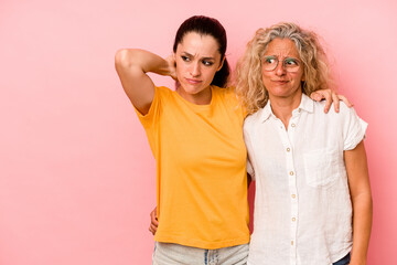 Caucasian mom and daughter isolated on pink background touching back of head, thinking and making a choice.