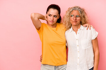 Caucasian mom and daughter isolated on pink background touching back of head, thinking and making a...