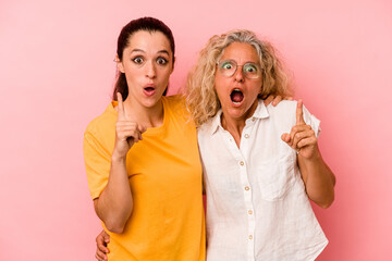 Caucasian mom and daughter isolated on pink background having an idea, inspiration concept.