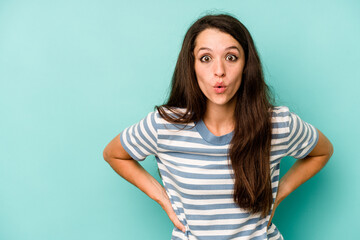 Young caucasian woman isolated on blue background being shocked because of something she has seen.