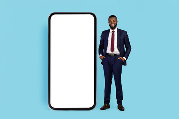 Successful Young Black Businessman In Suit Standing Near Huge Blank Smartphone