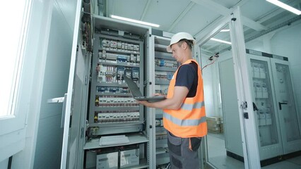 Electrical engineer working check the electric current voltage and overload at front of load center cabinet or consumer unit for maintenance in main power distribution system room.