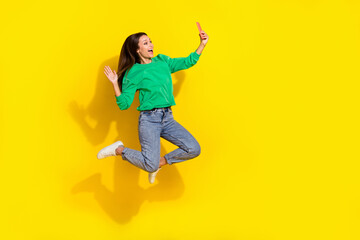 Full body photo of carefree lady jump hold telephone make selfie arm palm waving isolated on yellow color background