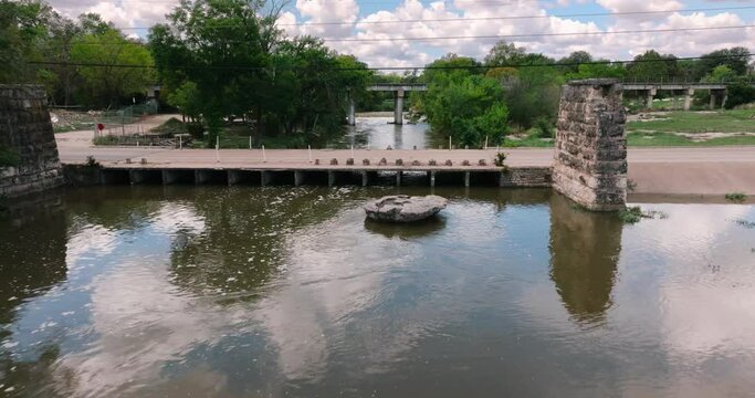Round Rock Memorial Park Chisholm Trail Train bridge and waterway aerial drone push in close up on the round rock on sunny day in 4k