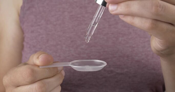 medicine drops for colds, woman with pipette drops syrup in a spoon High quality 4k footage
