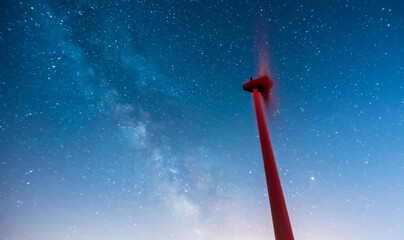 Industrial wind turbines, green energy windmill with a starry backgroun milky way night photography