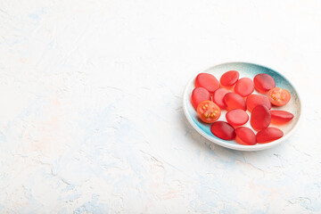 Jelly tomato candies on white concrete background. copy space, side view.