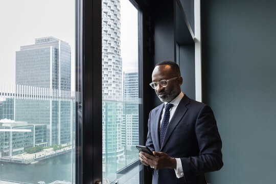 African American businessman using smartphone with view of city skyline