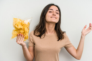 Young caucasian woman holding crisps isolated on yellow background receiving a pleasant surprise, excited and raising hands.