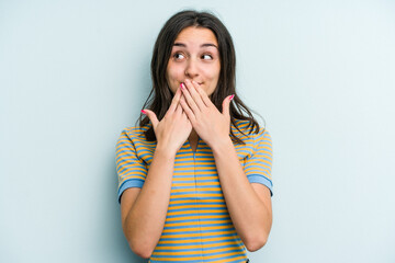 Young caucasian woman isolated on blue background shocked covering mouth with hands.