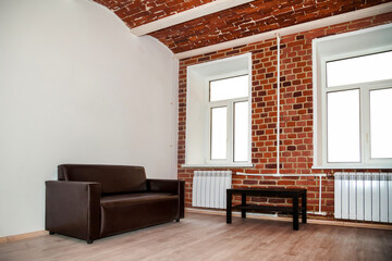 Background interior of room is designed in loft style with decorative red brick wall and furniture. Industrial design grunge interior with large space and decorative elements. Copy space