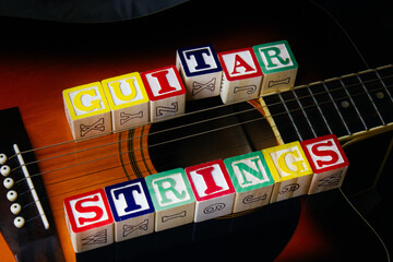 Word or phrase Guitar Strings made with letter cubes, standing on guitar.