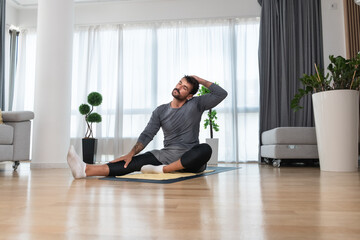 Young man rehabilitation exercise at home after car crash accident. Recovery workout of young guy with yoga training poses for stretching the muscles. Physical therapy exercising