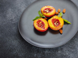Summer dessert - Cooking Ripe grilled peaches with honey and nuts over dark plate and table. Selective focus with blurred foreground and background. closeup