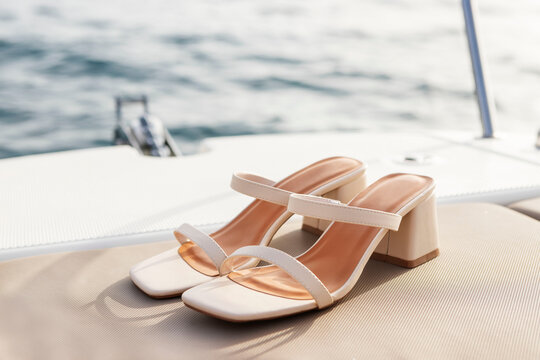Zapatos blancos de tacón sobre yate en alta mar atardecer.