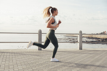 Woman running on promenade against sea and sky in summer