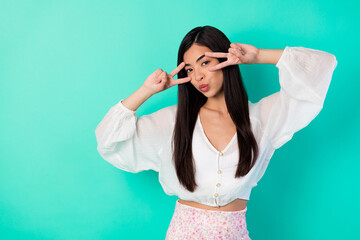 Portrait of adorable cute vietnamese person show v-sign near eyes kiss lips isolated on bright emerald color background