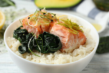 Tasty salmon with rice and spinach on white wooden table, closeup