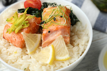Tasty salmon with rice and spinach on white wooden table, closeup