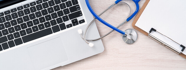 Stethoscope on laptop computer keyboard with medical record clipboard design concept.
