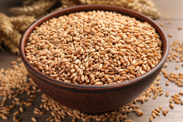 Wheat grains in bowl on wooden table, closeup