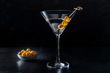 Martini, a glass with olives on a toothpick, on a dark background. Alcoholic cocktail with a place for text