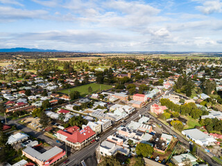 Sunlit aerial view of street corner with shops, houses and pub hotel roof painted with red flag