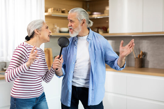Positive Senior Couple Having Fun In Kitchen Interior, Singing And Dancing