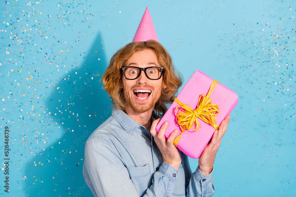 Sticker photo of excited sweet man wear denim shirt spectacles cap getting gift flying glitter isolated blue