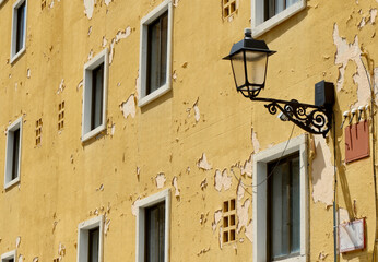 Damaged facade with simple windows and yellow peeling paint in Segovia, Spain