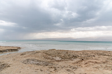 Exotic view of the sinkhole area of the Dead Sea on a stormy winter day. PhotoStorm and rain at the Dead Sea coastline. Salt crystals at sunset. The texture of the Dead sea. Salty seashore. High
